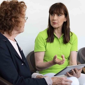 Zwei Frauen führen ein Beratungsgespräch im Wartezimmer einer Arztpraxis.