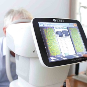 Eine Augenuntersuchung beim Augenarzt mit moderner TOMEY-Diagnosetechnik am Bildschirm.